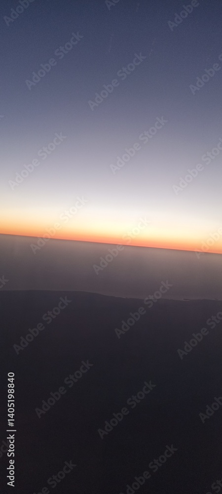 Sunset Horizon Captured from an Airplane. A mesmerizing view of the horizon at sunset, showcasing a gradient of colors from dark blue to orange, captured from an airplane window Sunset Horizon Captured from an Airplane. A mesmerizing view of the horizon at sunset, showcasing a gradient of colors from dark blue to orange, captured from an airplane window