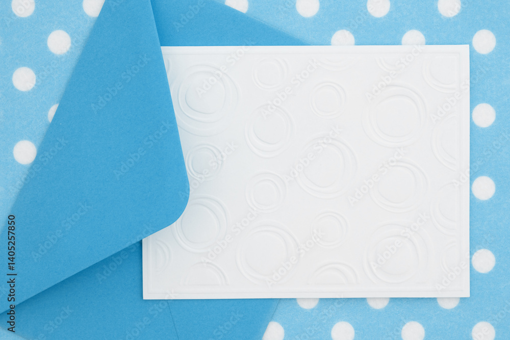 Blank greeting card and envelope on blue polka dots material