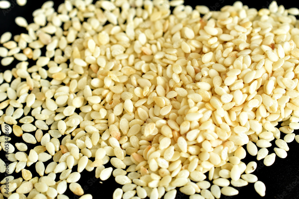 White sesame seeds lie on a black background. White sesame seeds lie on a black background.
