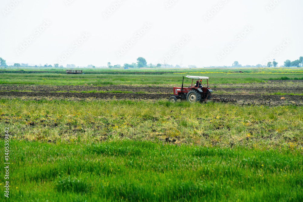 Obraz premium A tractor driving through the middle of a green field.