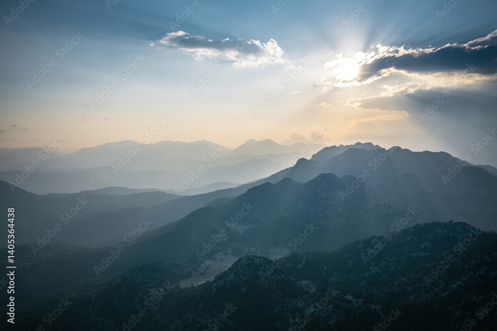 Dramatic sky with early morning sunrise with sun rays penetrating through the clouds onto the mountains.