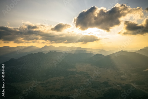 Obraz na płótnie Dramatic sky with yellow sun rays streaming through the clouds onto the mountains at sunrise in the early morning. w salonie