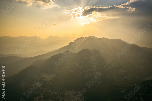 Obraz na płótnie Dramatic sky with early morning sunrise with sun rays penetrating through the clouds onto the mountains. w salonie