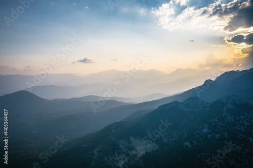 Obraz na płótnie An impressive sunrise skyscape in the early morning. Yellow sun rays filter through the clouds towards the mountains and the ground. w salonie