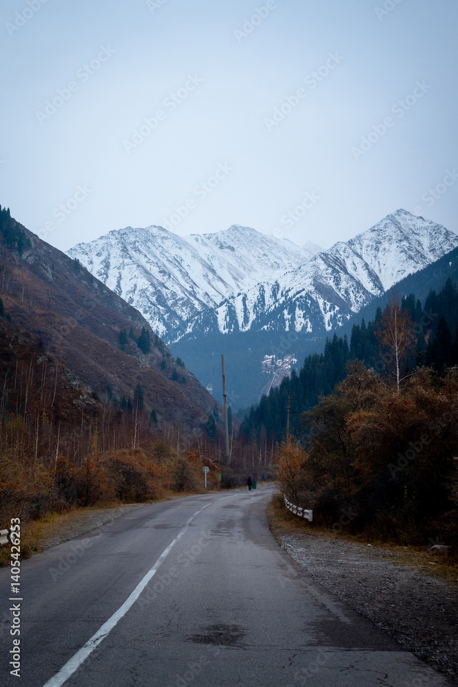 Naklejka premium Kyrgyzstan Scenic Mountain Road Leading to Snow-Capped Peaks in Autumn