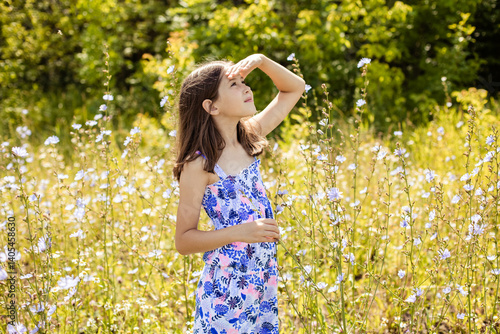 Cute teenage girl walking in the summer in the park and looking up, covering her face with her hand, close up