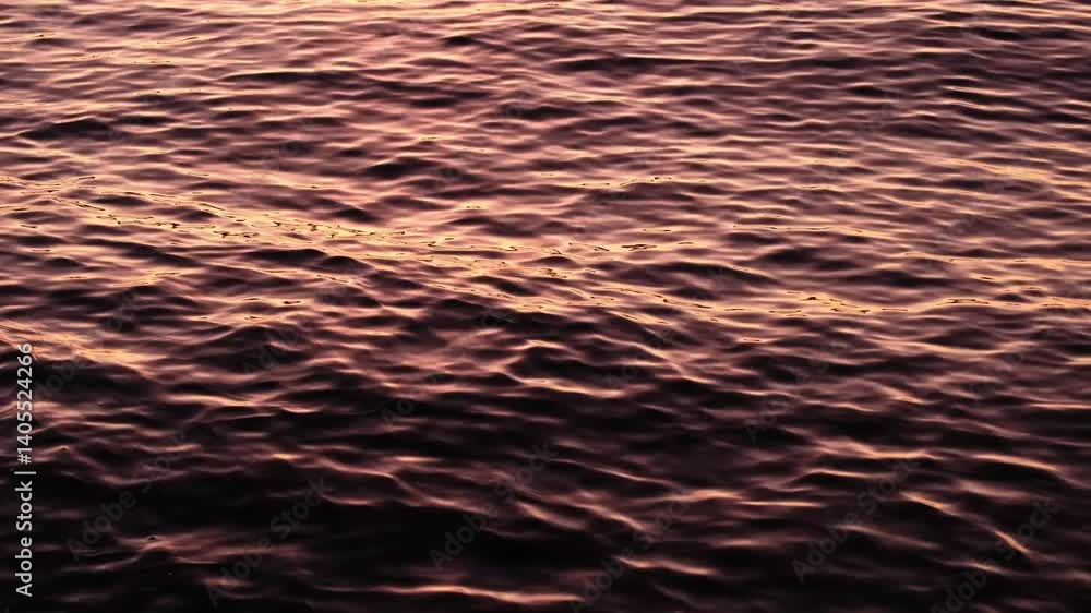 Beautiful pink and orange sunset reflections on dark blue water surface. Continuously changing wavy sea surface for background. Neutral mirror effect, calm and meditative nature concept. Beautiful pink and orange sunset reflections on dark blue water surface. Continuously changing wavy sea surface for background. Neutral mirror effect, calm and meditative nature concept.