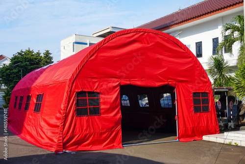 A large red tent stands on pavement, likely for social services or disaster relief purposes Use for aid and community support visuals