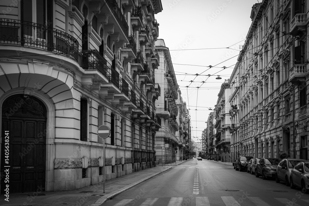 Fototapeta premium Bari city historic district with landmark buildings and cars parked alongside the road in Puglia (Apulia), Italy. A black and white photo.