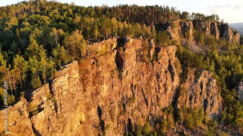 Breathtaking 4K Drone Flight Over Majestic Rocky Cliffs Covered in Lush Green Forest Bathed in Warm Golden Sunset Light - Cinematic Aerial View of a Scenic Nature Reserve from a Bird's-Eye Perspective