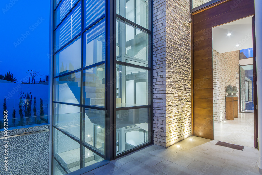 Sleek modern building showcases a combination of glass and stone materials, with a well-lit entrance and surrounding outdoor areas, creating a harmonious balance at dusk. Sleek modern building showcases a combination of glass and stone materials, with a well-lit entrance and surrounding outdoor areas, creating a harmonious balance at dusk.