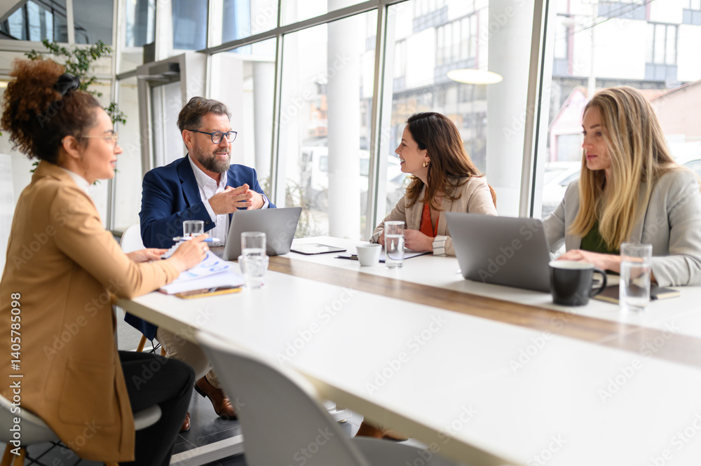 Male executive communicating with businesswoman while coworkers analyzing report in professional meeting