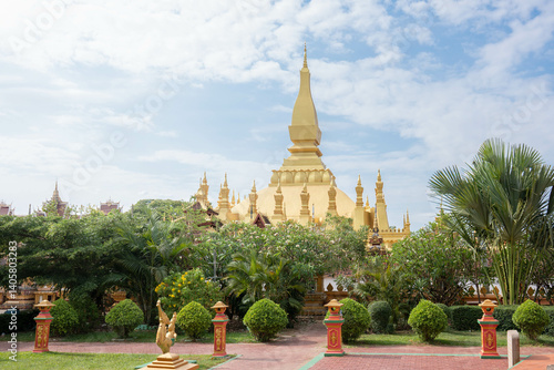 That Luang Stupa in Vientiane, Laos, shining brightly under a clear blue sky during the Lao New Year festival. The golden landmark represents national pride, peace, and spiritual heritage