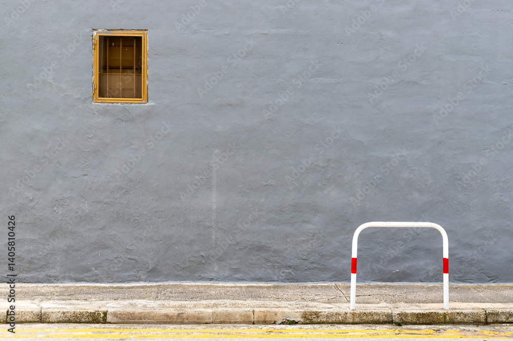 A dark gray wall with a small window in a metal frame, minimalist composition