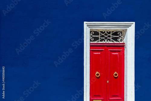 Obraz na płótnie High contrast photograph of dark blue wall of residential building facade with red door w salonie