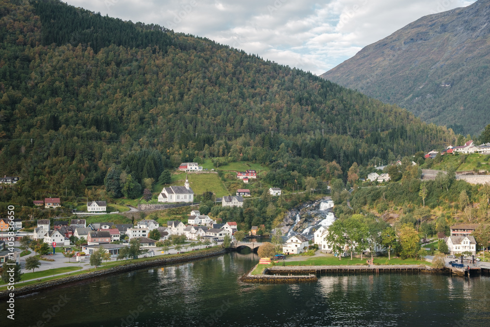 Fototapeta premium The small Norwegian town Hellesylt in the sunlight with mountains in the background in Norway.