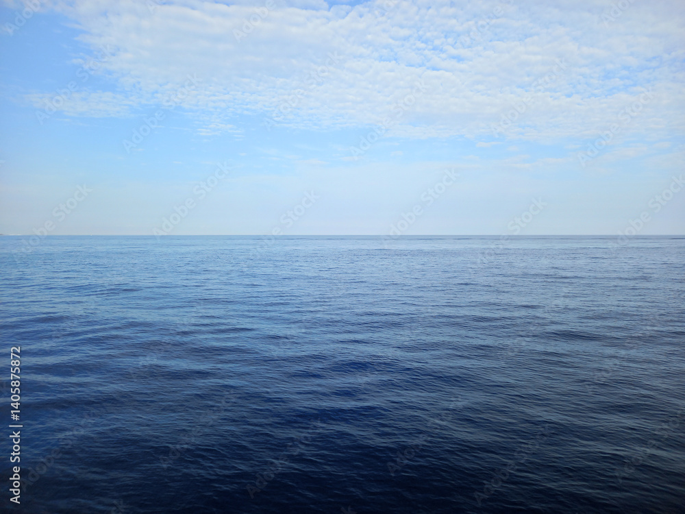 Fototapeta premium Panoramic view of a calm sea. Background of the horizon with ocean and a blue sky with white clouds. Maritime landscapes. Relaxation and seabeds.
