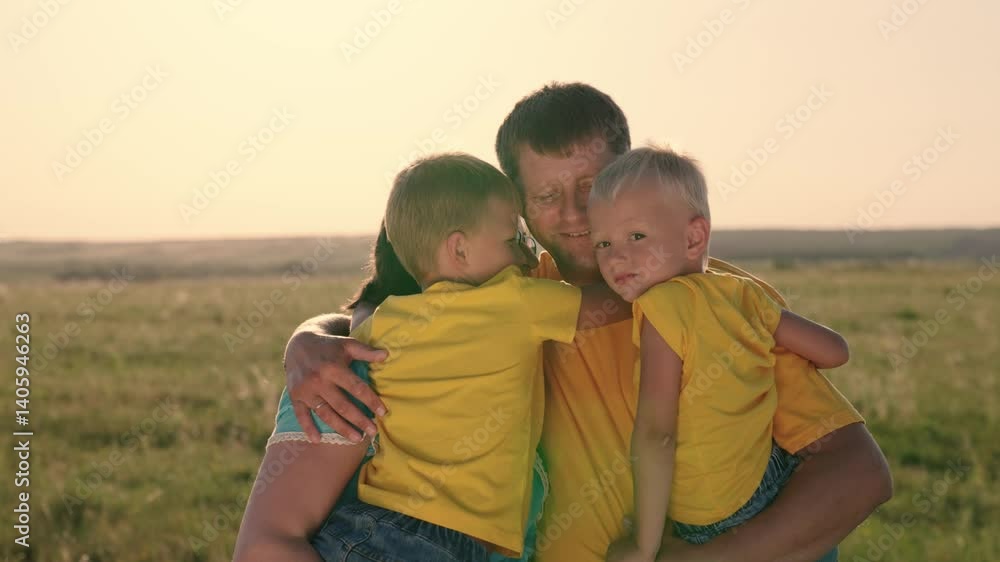 Father farmer hugs sons and wife in the field at sunset, woman with husband and kid walk in nature together and smile, love in a happy family, teamwork, business concept, weekend summer vacation. Father farmer hugs sons and wife in the field at sunset, woman with husband and kid walk in nature together and smile, love in a happy family, teamwork, business concept, weekend summer vacation.