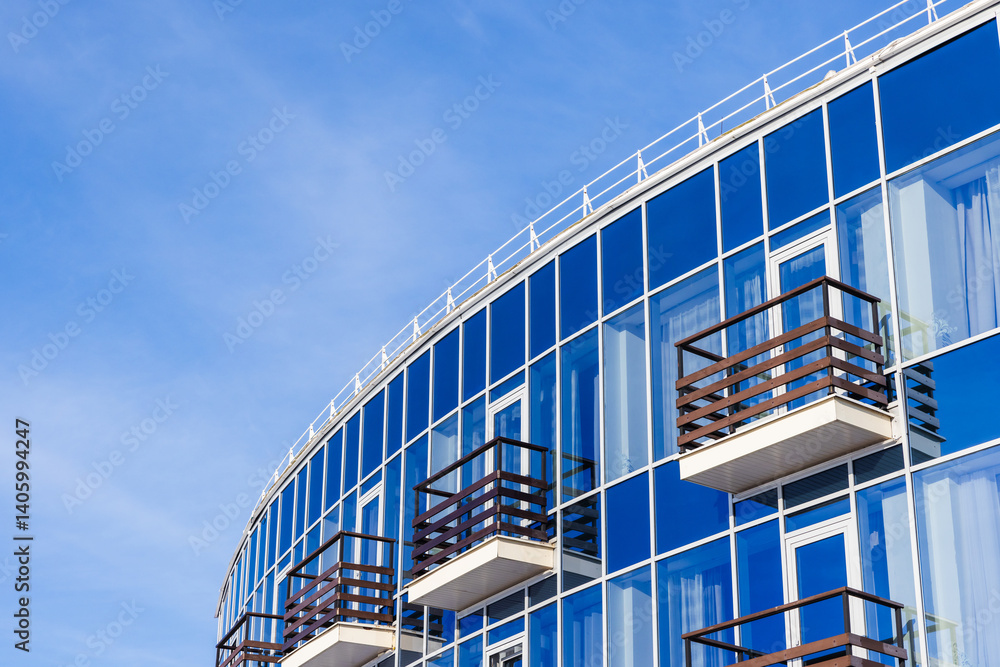 Blue glass building featuring wooden balconies, reflecting the sky