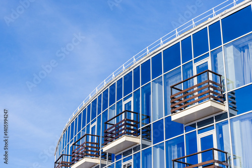 Obraz na płótnie Blue glass building featuring wooden balconies, reflecting the sky w salonie