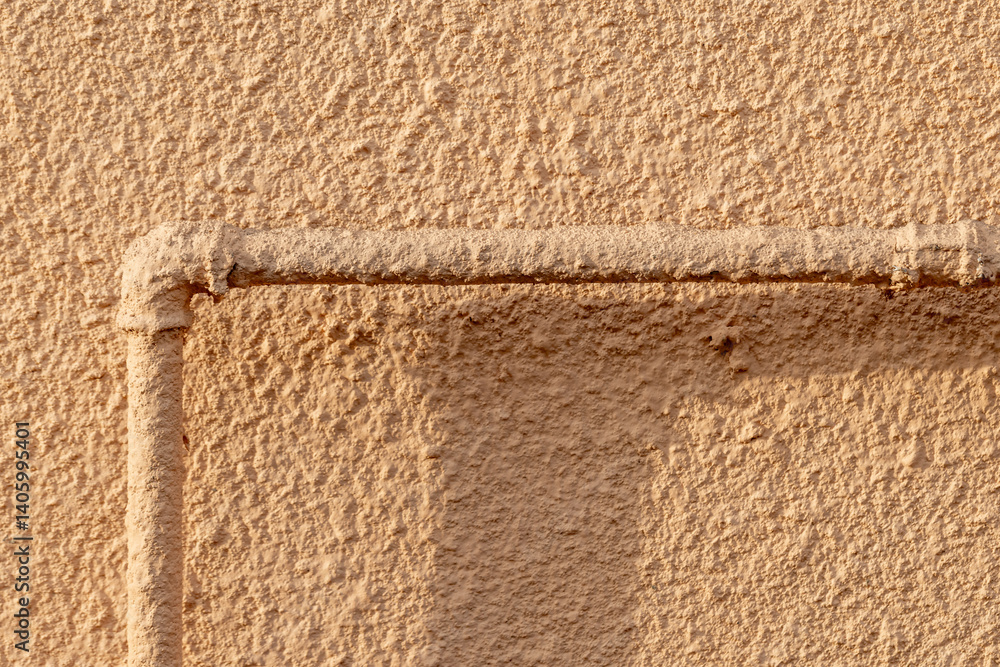 Rourh industrial beige wall with a pipe. Abstract background texture