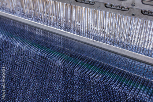 Quadro su tela Close-up of modern industrial loom weaving blue textile fabric with tight thread alignment