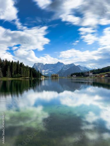 Famous view of misurina lake with mountain range in background on beautiful blue sky day, shot in long exposure