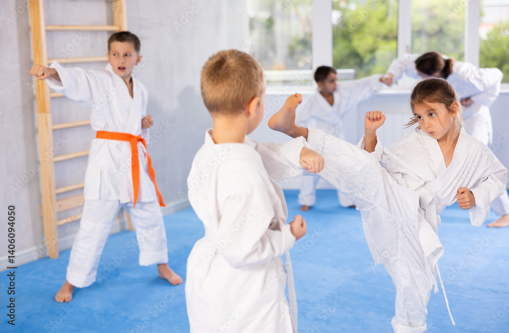 Karate kids in kimono sparring together during their group karate training