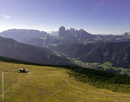 Aerial view of mountain Sassolungo and surrounding valley and meadows with Raschotz hut in foreground