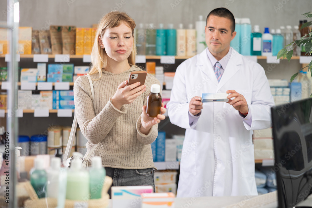 Selective young woman scanning QR on syrup while pharmacist consulting her in chemistry Selective young woman scanning QR on syrup while pharmacist consulting her in chemistry