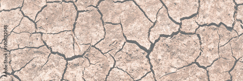 Texture of cracked dried soil. Dry ground with cracks. Brown rough surface of the soil during summer drought. Wide panoramic background for design. Ecology, climate change and global warming on Earth.