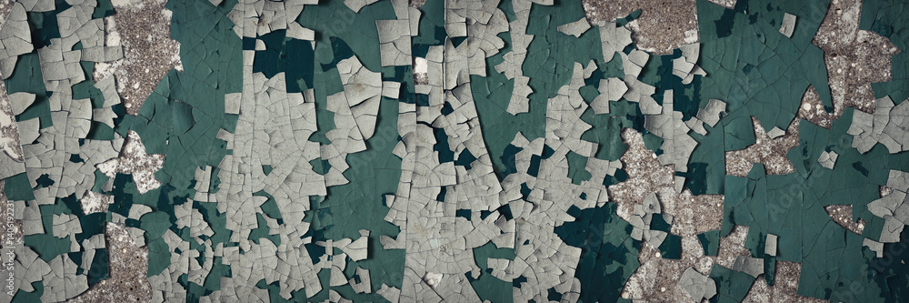 Peeling paint on the wall. Panorama of a concrete wall with old cracked flaking paint. Weathered rough painted surface with patterns of cracks and peeling. Panoramic texture for background and design.