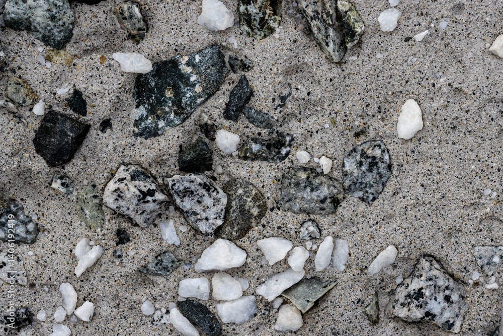 Concrete wall texture with pebbles. Decorative rough concrete surface with white, black and gray stones. Perfect for background and design. Closeup. High resolution.