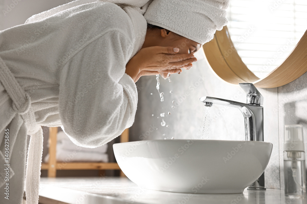 Woman washing her face over sink in bathroom