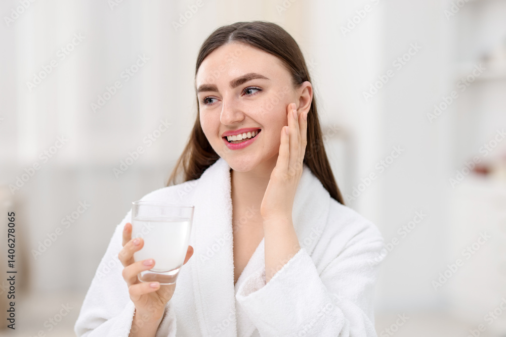 Smiling woman with glass of collagen water on blurred background Smiling woman with glass of collagen water on blurred background