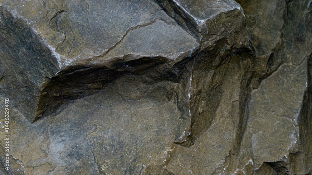 Naklejka premium Close up of a rough textured rock surface. Stone exhibits various shades of gray and brown. With visible cracks and uneven layers suggesting a natural weathered formation.