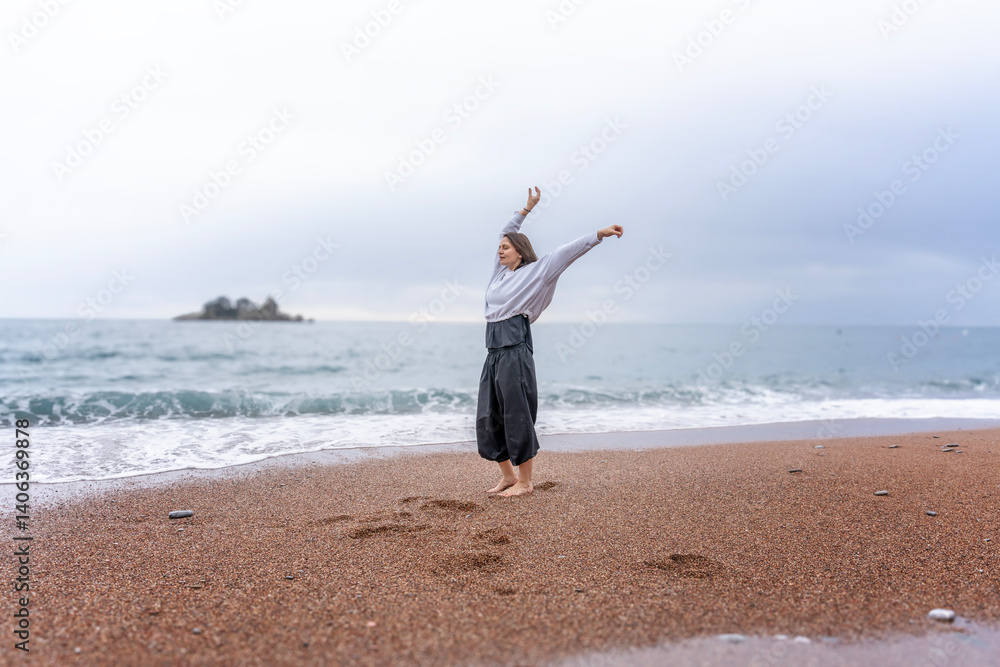 Woman dancing on sandy seashore in rainy weather, mindful movement dance meditation concept