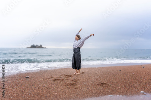 Obraz na płótnie Woman dancing on sandy seashore in rainy weather, mindful movement dance meditation concept w salonie