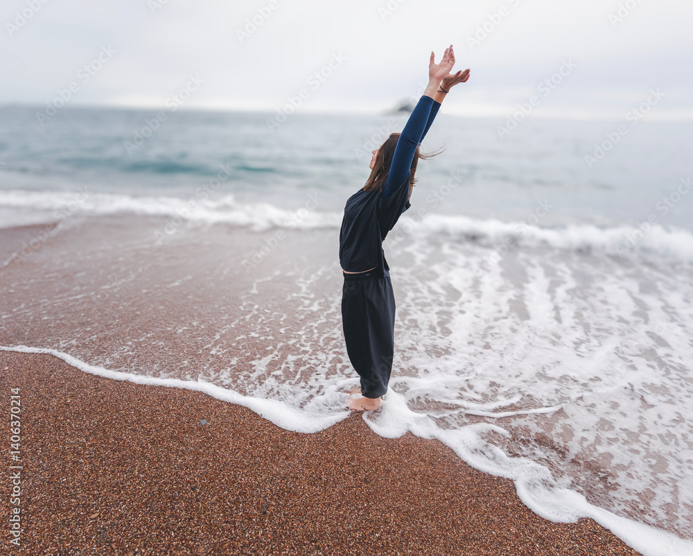 Woman dancing on sandy seashore in rainy weather, mindful movement dance meditation concept