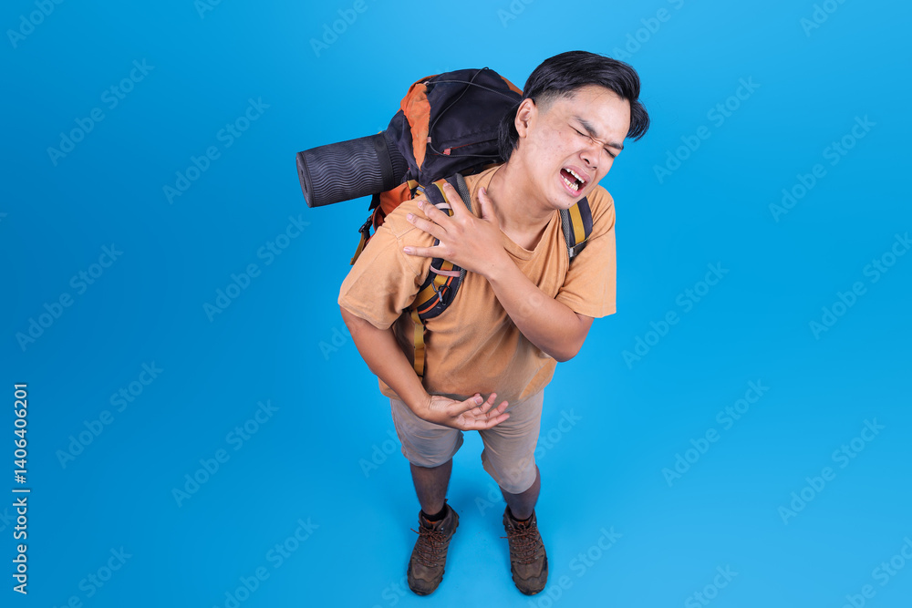 Overhead View Of Young Asian Traveler Man Feeling Painful On Shoulder Over Blue Background Overhead View Of Young Asian Traveler Man Feeling Painful On Shoulder Over Blue Background