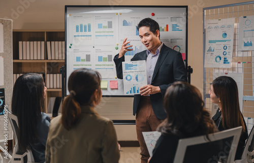 Foto Asian businessman leads a presentation in a modern office, using charts and grap