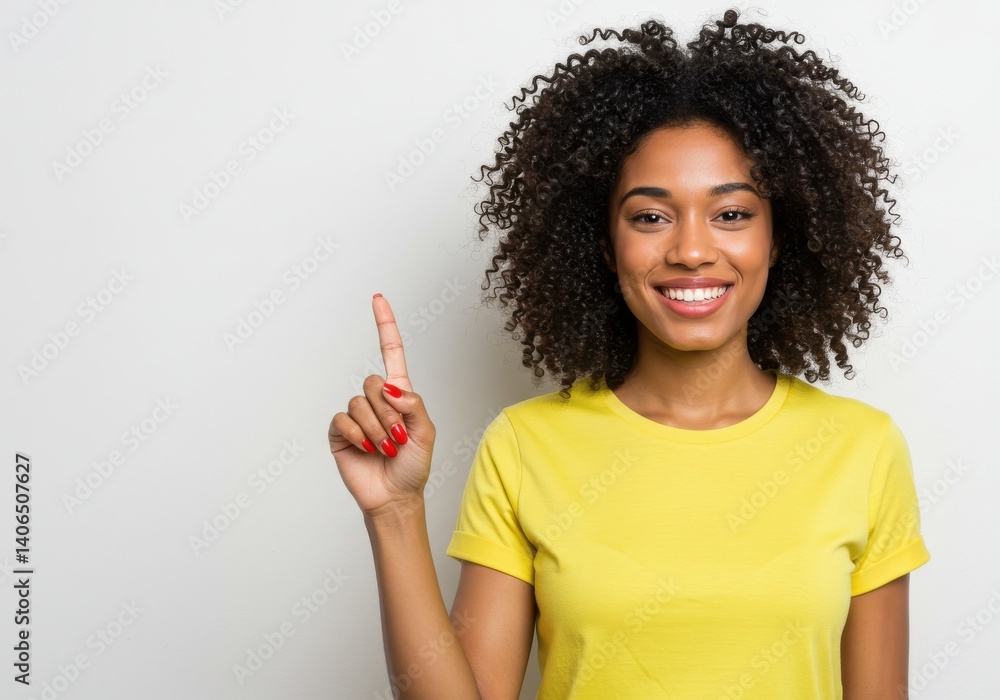 Portrait of a smiling woman with curly hair pointing upwards wearing a yellow shirt on white background Portrait of a smiling woman with curly hair pointing upwards wearing a yellow shirt on white background