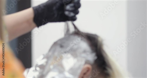 Man dyes her hair in blond , female hairdresser. 