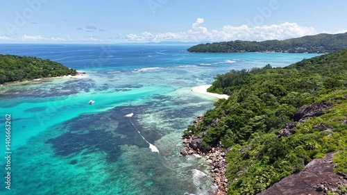 Praslin Island, Seychelles, with lush green hills, turquoise sea, and scenic tropical coastline under a clear blue sky.
