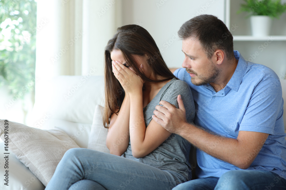 Sad woman being comforted by friend or partner at home Sad woman being comforted by friend or partner at home