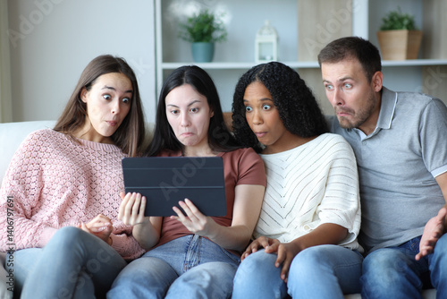 Perplexed group of friends checking tablet at home
