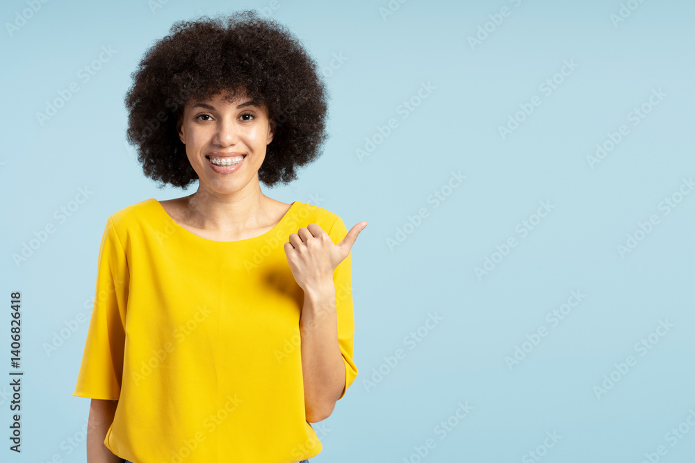 Smiling African American woman pointing finger showing something on blue background Smiling African American woman pointing finger showing something on blue background