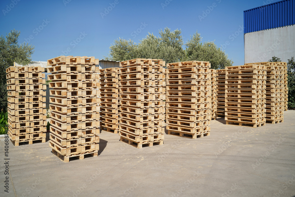 Stacked Wooden Pallets Outdoors in a Storage Facility on a Sunny Day.