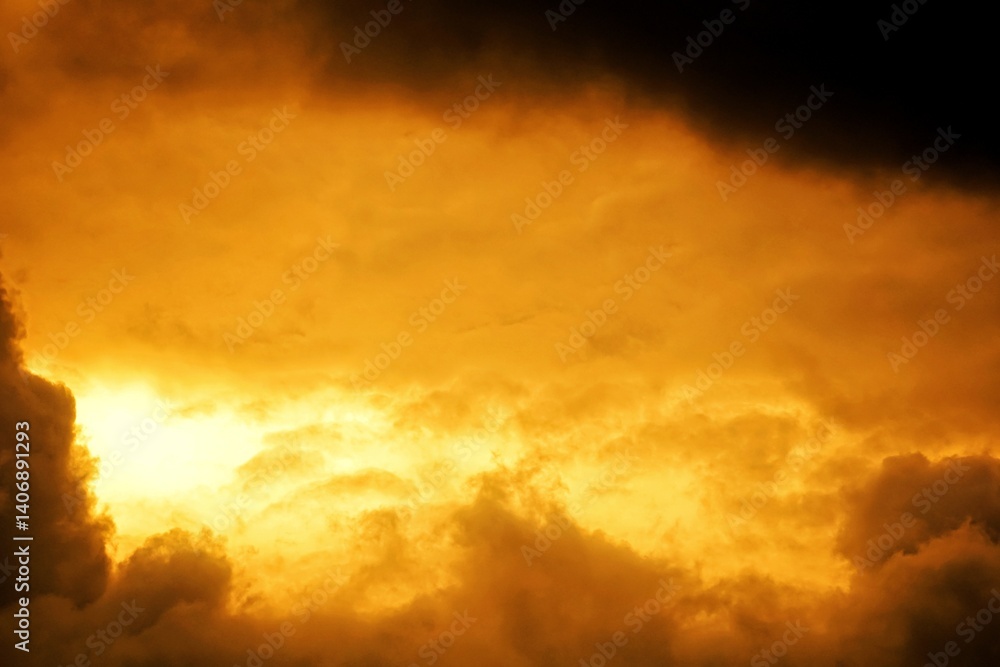 Fototapeta premium Dramatic clouds gather at sunset, their soft peaks illuminated by the fading light of day.