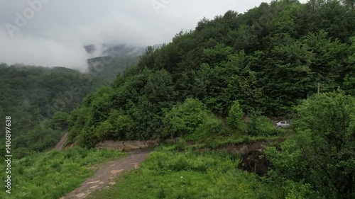 Aerial of the rain falling over the green mountains of Gosh village, Armenia during a foggy daytime